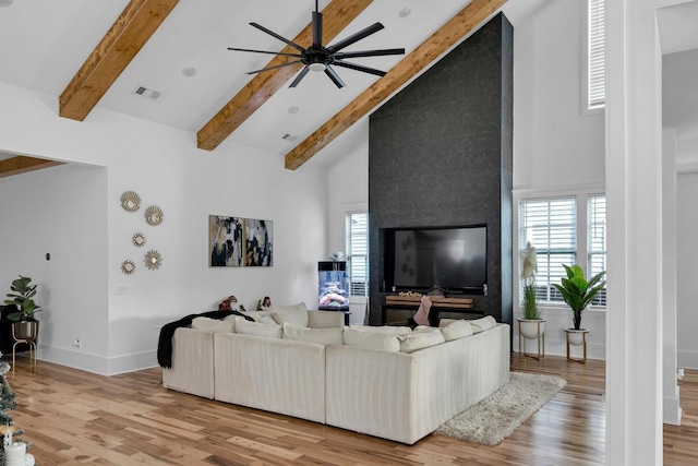 living room with a healthy amount of sunlight, light wood-type flooring, and high vaulted ceiling