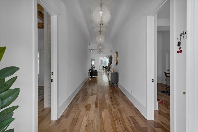 corridor with light wood finished floors and baseboards