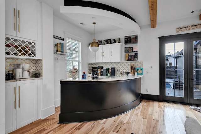 kitchen with beam ceiling, light wood-type flooring, visible vents, and white cabinets