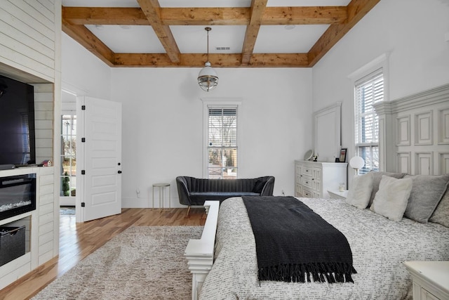 bedroom with light wood finished floors, multiple windows, coffered ceiling, and beam ceiling