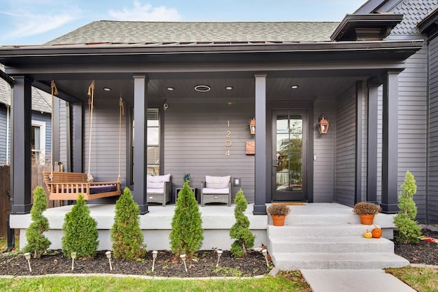 entrance to property featuring covered porch and a shingled roof