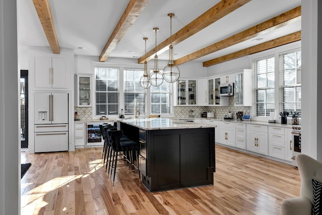 kitchen featuring paneled built in fridge, beverage cooler, white cabinets, stainless steel microwave, and a center island