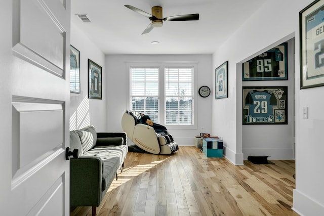 sitting room featuring wood-type flooring, visible vents, ceiling fan, and baseboards