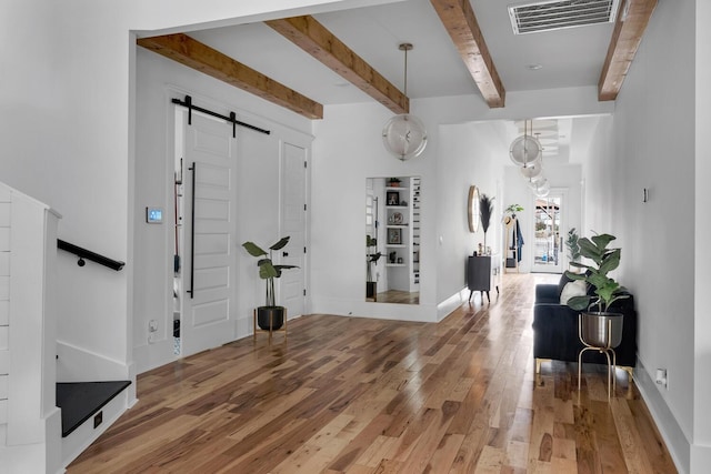 entryway featuring a barn door, visible vents, baseboards, hardwood / wood-style flooring, and beamed ceiling