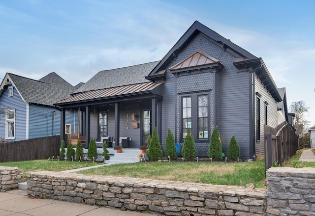 view of front of property featuring covered porch, metal roof, a standing seam roof, and fence