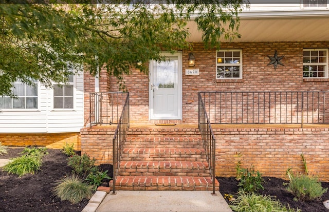 view of exterior entry featuring brick siding and a porch