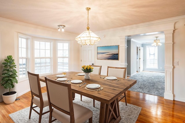 dining area with ornate columns, crown molding, baseboards, and light wood-style floors