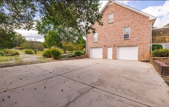 view of side of property with an attached garage, driveway, and brick siding