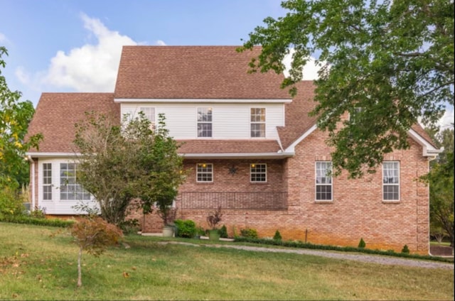 exterior space featuring brick siding, a yard, and roof with shingles