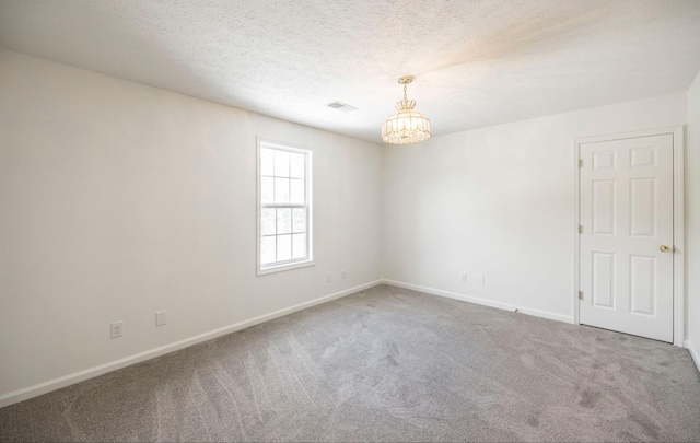 carpeted empty room featuring a notable chandelier, visible vents, baseboards, and a textured ceiling