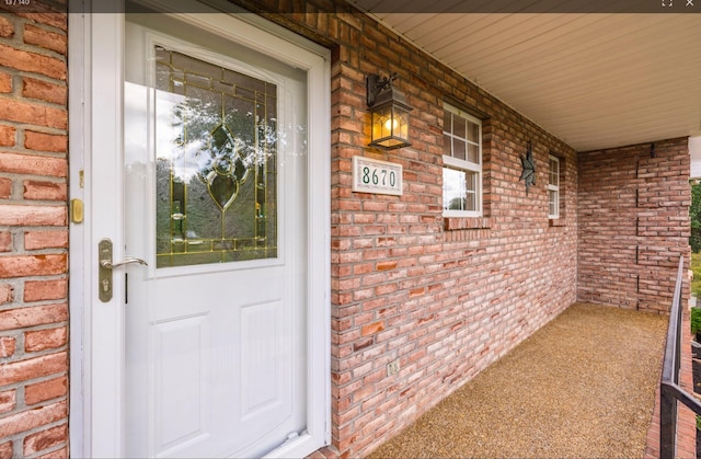 entrance to property featuring covered porch and brick siding