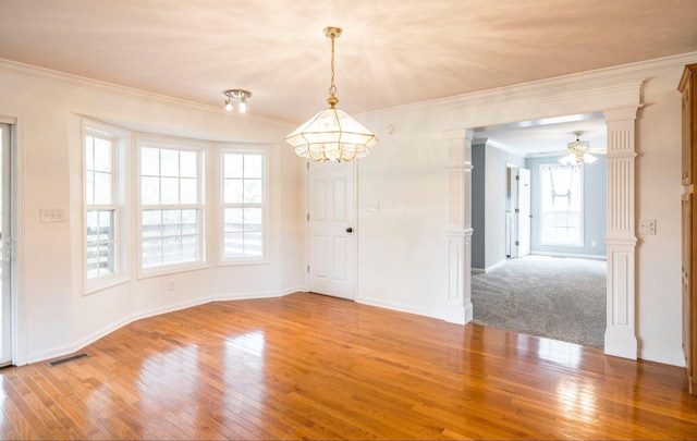 spare room featuring ornate columns, visible vents, light wood-style floors, and ornamental molding