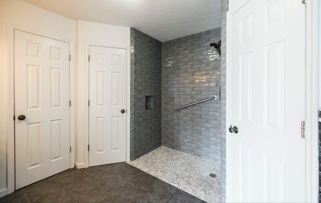 bathroom featuring tiled shower, a textured ceiling, and tile patterned floors