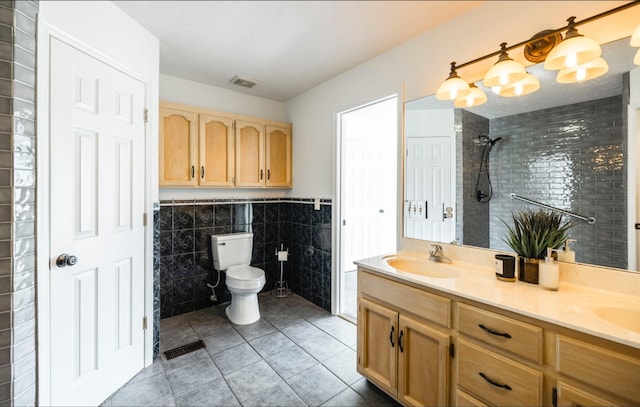 full bathroom featuring tile walls, visible vents, toilet, a sink, and tiled shower