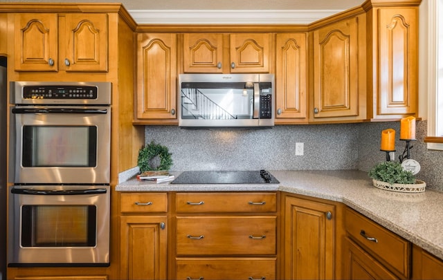 kitchen with appliances with stainless steel finishes, brown cabinetry, and light countertops