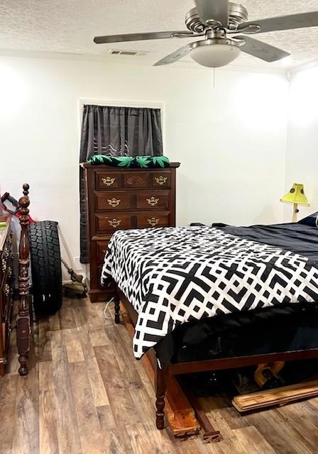 bedroom with visible vents, ceiling fan, a textured ceiling, and wood finished floors