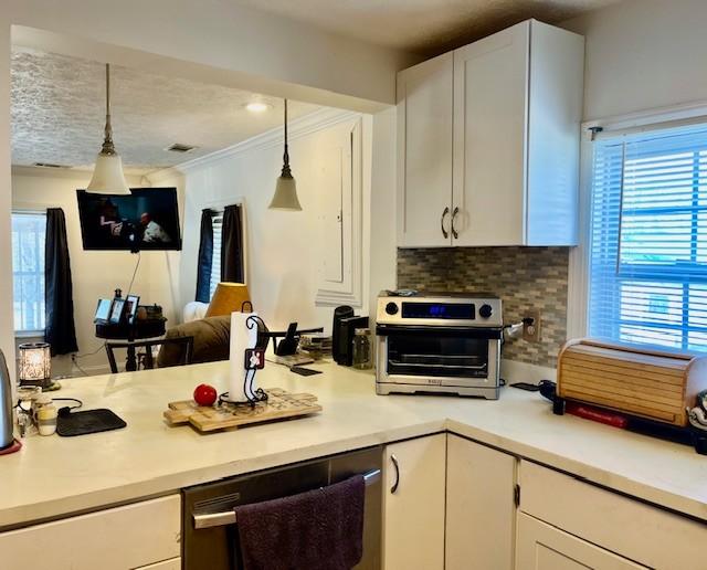 kitchen featuring dishwashing machine, tasteful backsplash, light countertops, and white cabinets