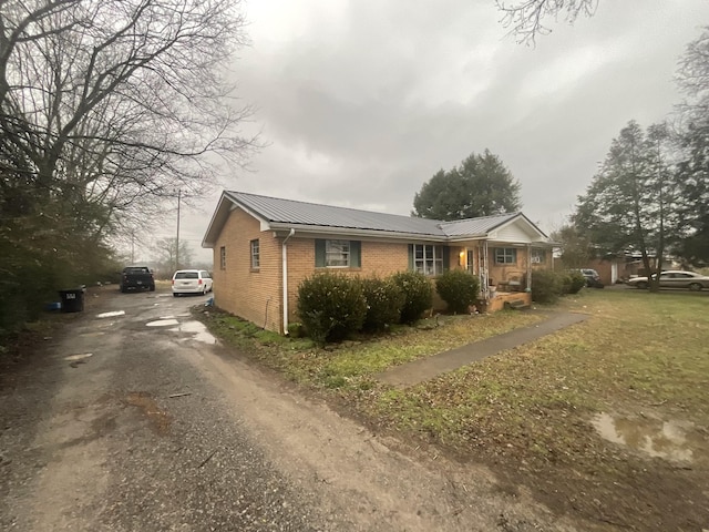 view of front of home with brick siding, metal roof, and driveway