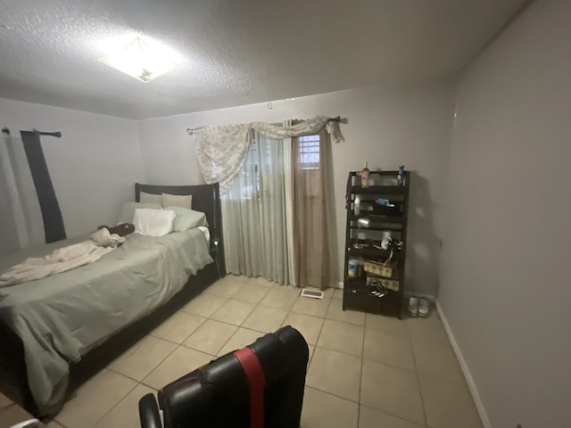 bedroom with a textured ceiling, baseboards, and light tile patterned floors