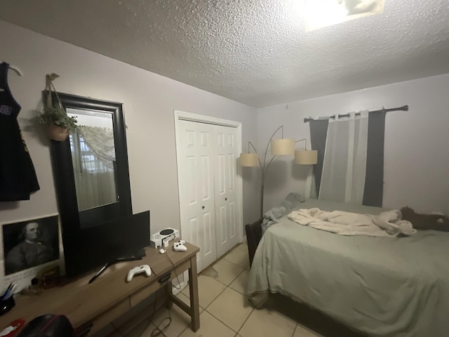 bedroom with light tile patterned floors, a textured ceiling, and a closet