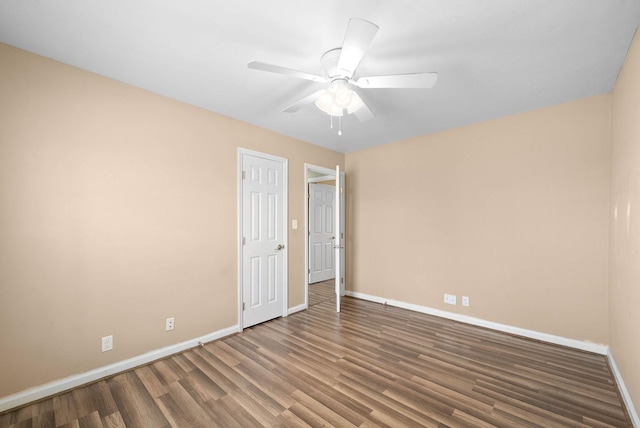 empty room with wood finished floors, a ceiling fan, and baseboards