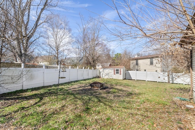 view of yard with an outbuilding, a storage shed, an outdoor fire pit, and a fenced backyard