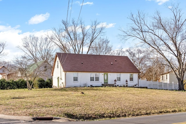 view of front of home with roof with shingles, a front yard, and fence