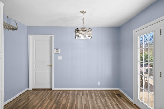 unfurnished dining area featuring an inviting chandelier, wood finished floors, visible vents, and baseboards