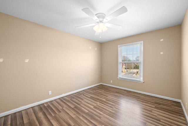 empty room with ceiling fan, wood finished floors, visible vents, and baseboards