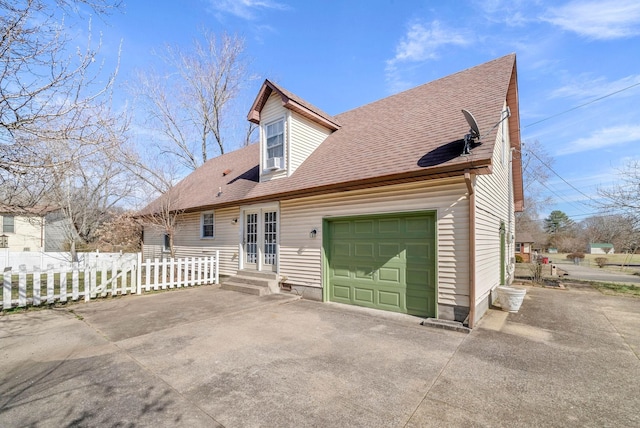 rear view of property featuring a garage, fence, concrete driveway, and french doors