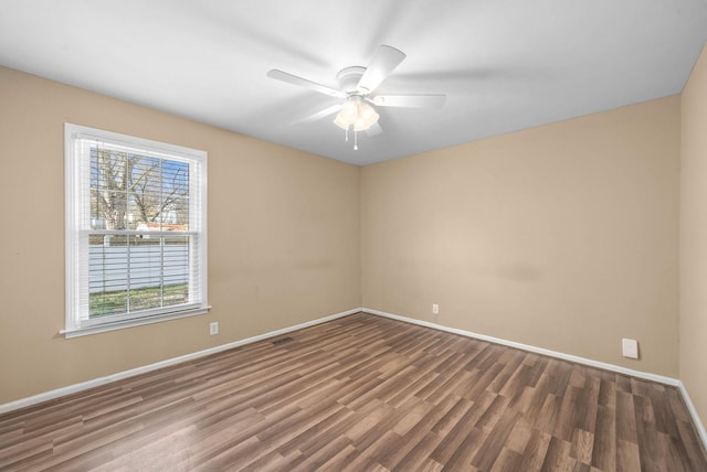 empty room featuring ceiling fan, wood finished floors, visible vents, and baseboards