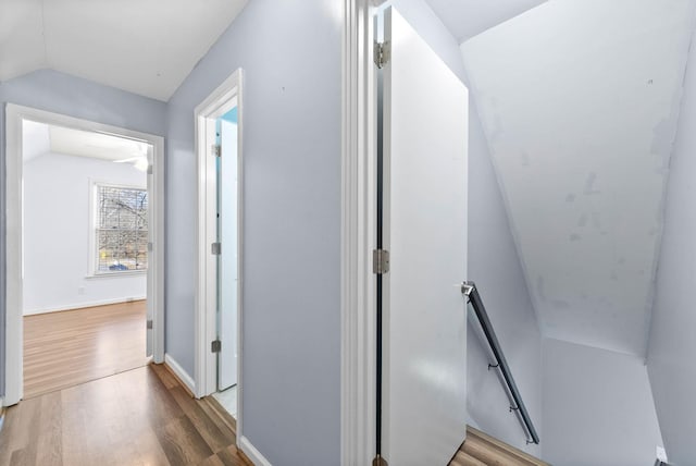 corridor with lofted ceiling, baseboards, an upstairs landing, and wood finished floors