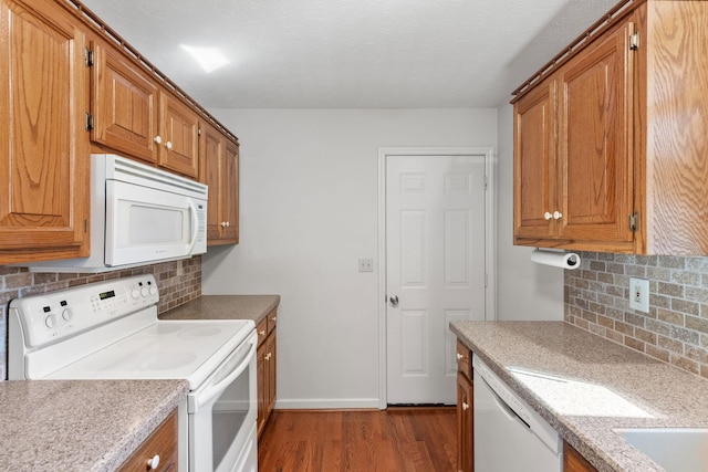 kitchen featuring brown cabinetry, white appliances, light countertops, and dark wood-style flooring