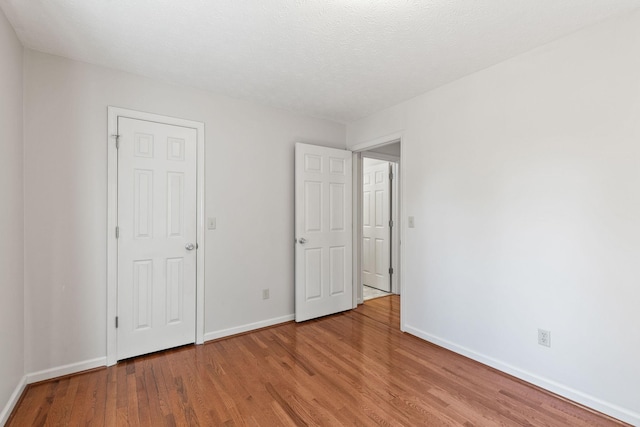 unfurnished bedroom featuring a textured ceiling, wood finished floors, and baseboards