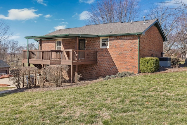 back of house with a yard, a shingled roof, a deck, and brick siding