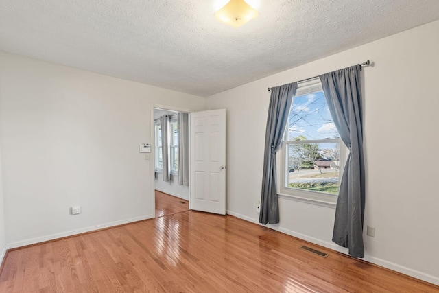 spare room with visible vents, light wood-style flooring, and baseboards