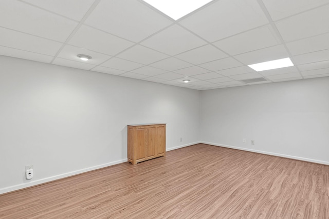 unfurnished room featuring light wood-type flooring, baseboards, and a paneled ceiling