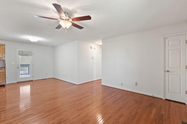 spare room with ceiling fan, a textured ceiling, baseboards, and light wood-style floors