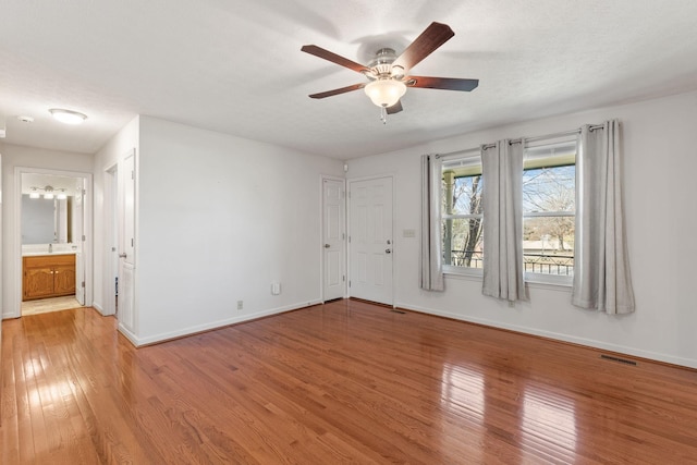 interior space with visible vents, ceiling fan, a textured ceiling, light wood-type flooring, and baseboards