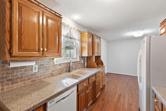 kitchen with white appliances, brown cabinets, a sink, and backsplash