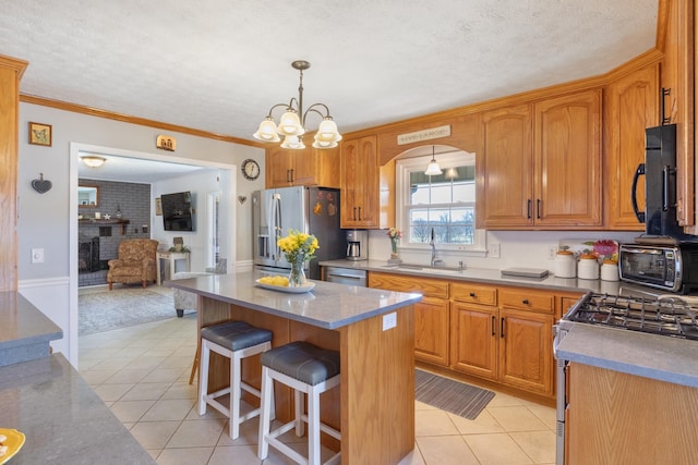 kitchen with light tile patterned floors, stainless steel appliances, a textured ceiling, a kitchen bar, and a sink