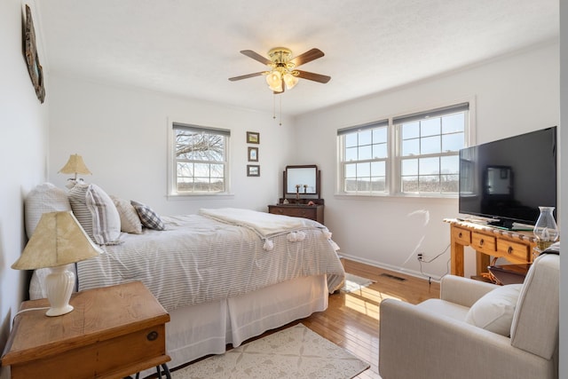 bedroom with wood-type flooring, multiple windows, visible vents, and baseboards