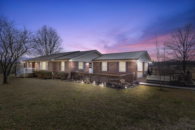 view of front of house featuring a deck, a lawn, and brick siding