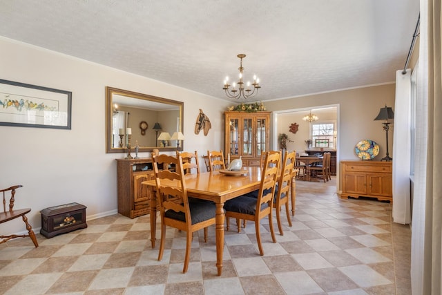 dining room featuring a textured ceiling, ornamental molding, baseboards, and an inviting chandelier