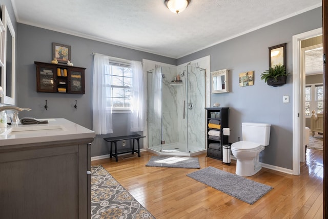 bathroom featuring ornamental molding, a marble finish shower, toilet, and hardwood / wood-style flooring