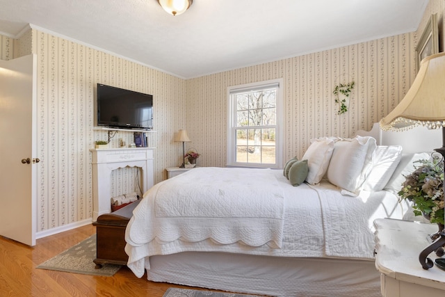 bedroom featuring wallpapered walls, baseboards, crown molding, and wood finished floors