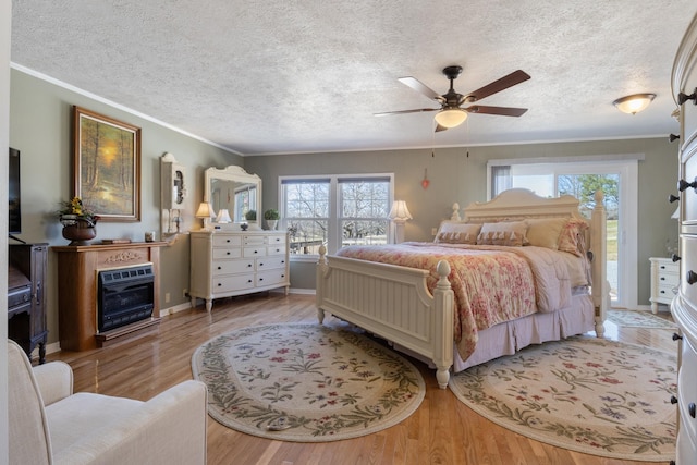 bedroom featuring a textured ceiling, ornamental molding, a fireplace, and wood finished floors