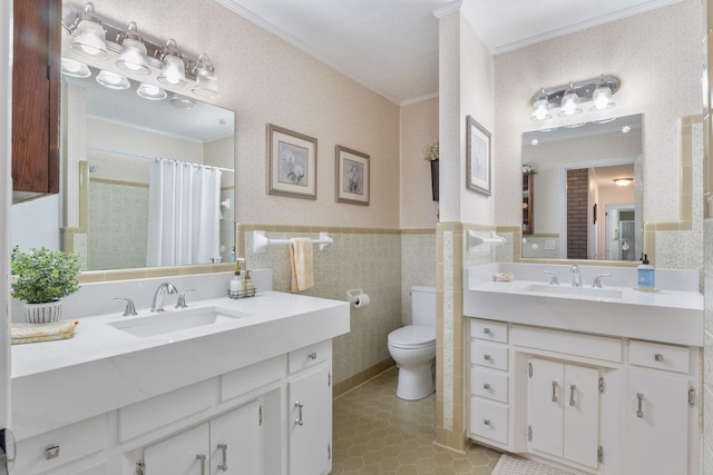 bathroom featuring crown molding, tile walls, a sink, and wainscoting