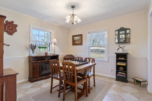 dining room featuring wallpapered walls, baseboards, crown molding, and an inviting chandelier