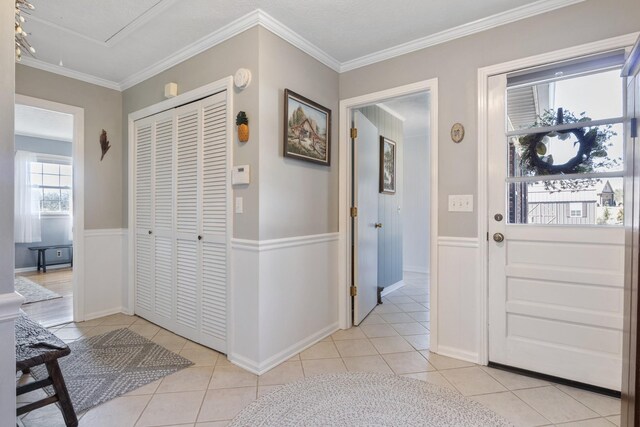 foyer entrance with ornamental molding and light tile patterned floors